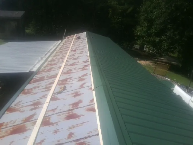 Old rusted panels beside newly installed green metal roofing — Wind Damage Roof Repair by Roofing Brothers in Boulder