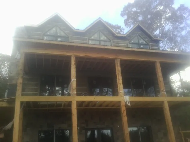 Dormers and porch framing on a large log home under construction — Roof Coating work by our crew in Boulder