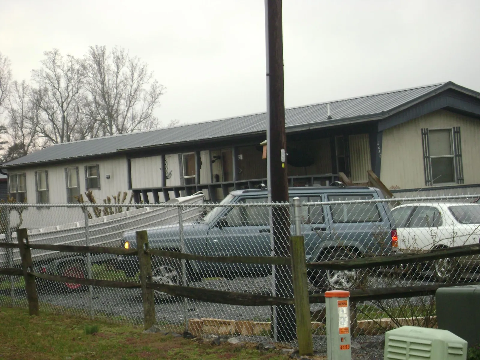 Dark metal roof on a long single story building behind a chain link fence in Boulder