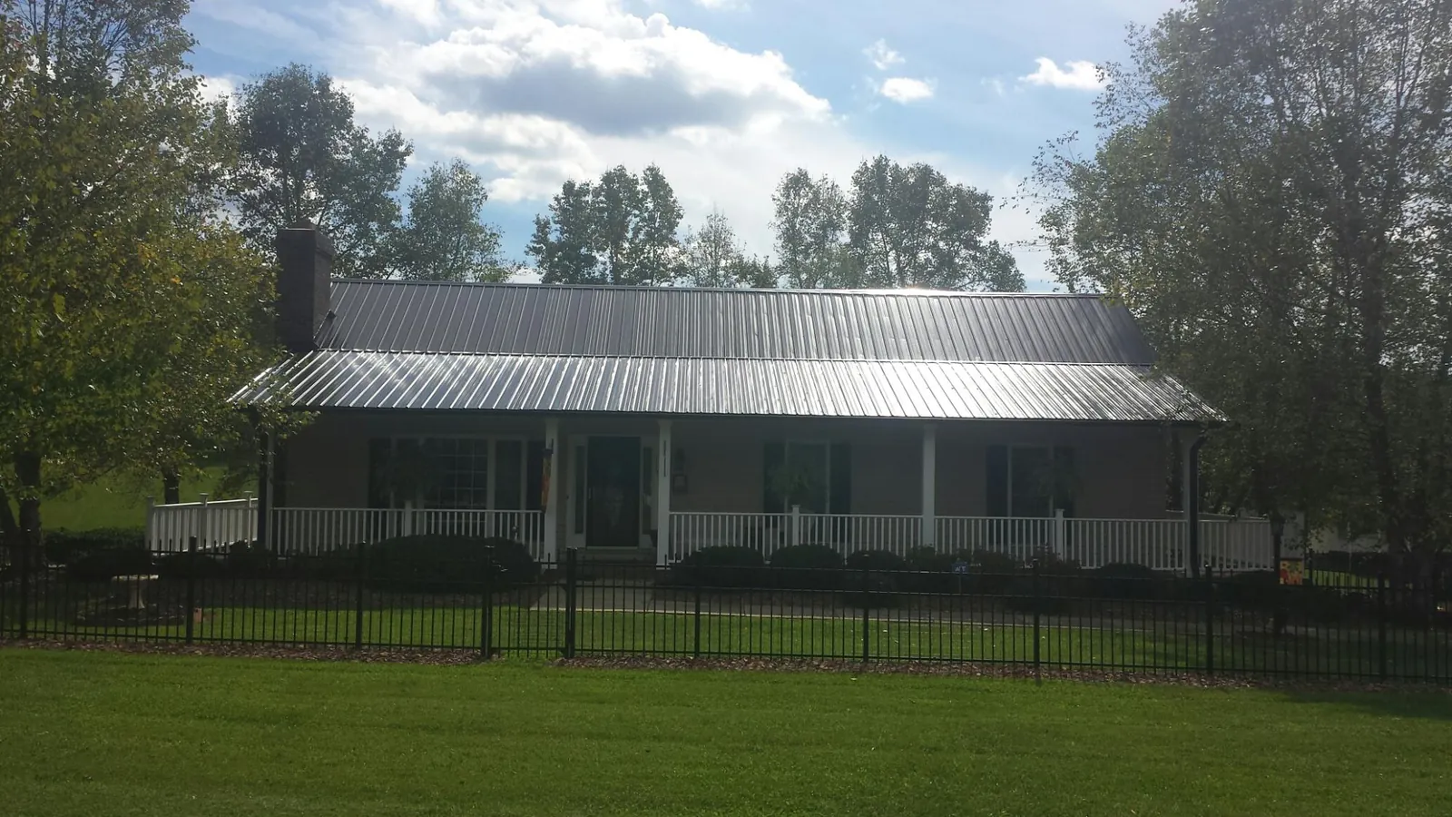 Gray metal roof on a brick ranch with a full width front porch — Gutter Guard Installation work by our crew in Boulder
